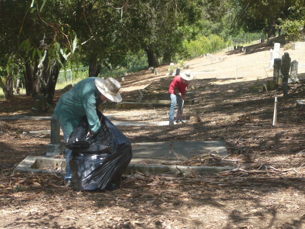 Carol Wiley and Harlan Stickland (background) team up to clean up fallen debris on the graves along the Carquinez Scenic Drive edge of the Alhambra Cemetery ground on Saturday. (DAVID SCHOLZ / Martinez Tribune)